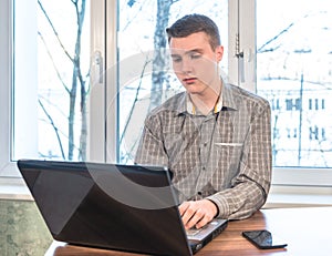 Young man working on laptop at home at the table.