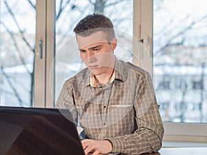 Young man working on laptop at home at the table.