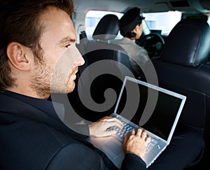 Young man working on laptop in limousine