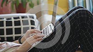 Young man working with laptop lying on sofa in room.