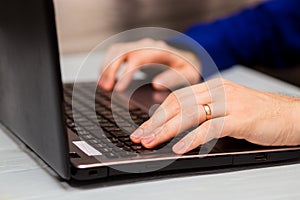 Young man working with laptop, man`s hands on notebook computer