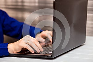 Young man working with laptop, man`s hands on notebook computer