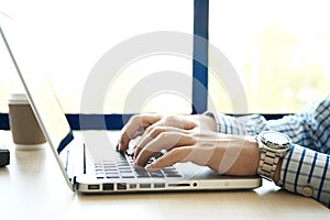 Young man working with laptop, man's hands on notebook computer