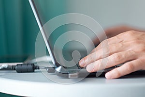 Young man working with laptop, man`s hands on notebook computer, business person at workplace