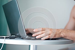 Young man working with laptop, man`s hands on notebook computer, business person at workplace