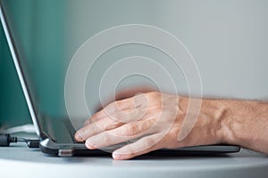 Young man working with laptop, man`s hands on notebook computer, business person at workplace