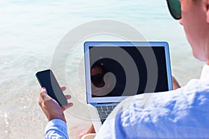 Young man working on laptop at tropical beach