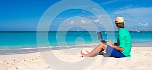 Young man working on laptop at tropical beach