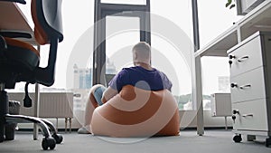 Young man working in modern office sitting on the sandbag