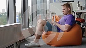Young man working in modern office sitting on the sandbag