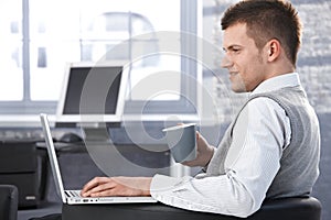 Young man working in office using laptop