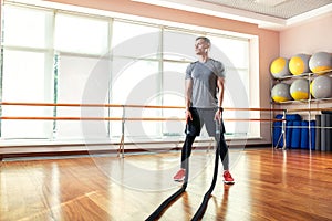 Young man working out with battle ropes at a gym