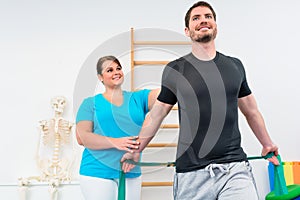Young man working out with physiotherapist and resistance band