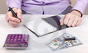 A young man working at a table using a calculator and a notebook.