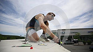 Young man is working on top of a trailer van patching the roof, USA