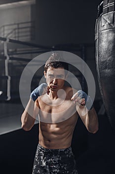 The young man workout a kick on the punching bag in gym