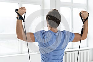 Young man during workout with a resistance bands in the gym
