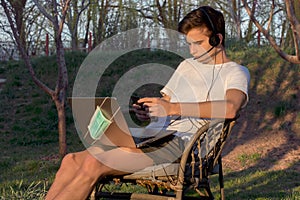 Young man works from home, relaxed in isolation, on a laptop with a helmet in the garden