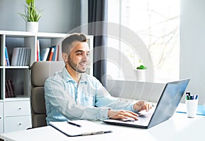 Young Man Works while Sitting in front of a Computer at Home. The Workplace of a Professional Worker, Freelancer or