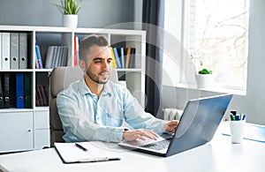 Young Man Works while Sitting in front of a Computer at Home. The Workplace of a Professional Worker, Freelancer or