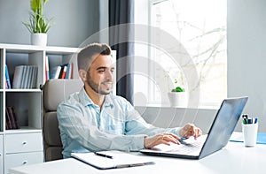 Young Man Works while Sitting in front of a Computer at Home. The Workplace of a Professional Worker, Freelancer or