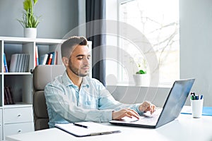 Young Man Works while Sitting in front of a Computer at Home. The Workplace of a Professional Worker, Freelancer or