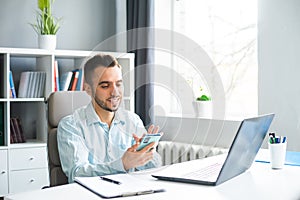 Young Man Works while Sitting in front of a Computer at Home. The Workplace of a Professional Worker, Freelancer or