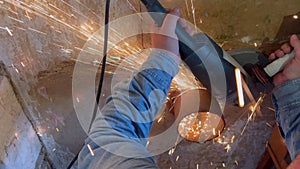 Young man works using angle grinder machine on steel pipe