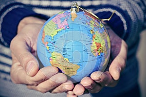 Young man with a world globe as a christmas ball in his hands