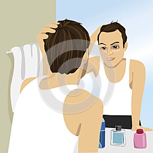 Young man worried about hair loss while looking in mirror
