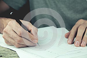 A young man writes with a pen on a notebook