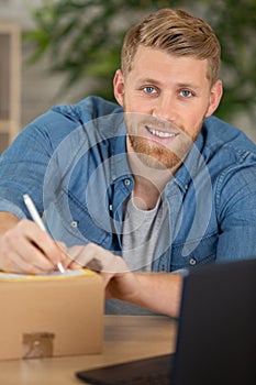 young man writing address to send package