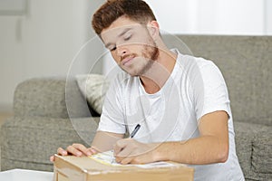 young man writing postage label for parcel