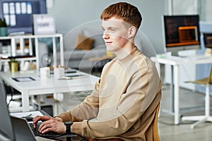Young man writing programming code on computer