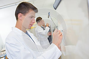 Young man writing on whiteboard