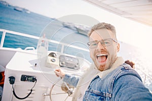 Young man yacht driver takes selfie photo, concept of trip maldives or egypt by boat travel summer