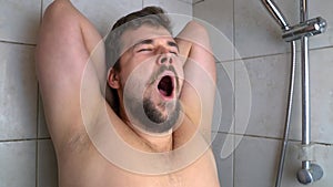 A young man yawns in the shower