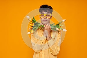 A young man in yellow glasses with a bouquet of flowers holiday unaltered