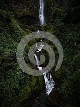 Young man in yellow jacket in front of El Chorro de Giron waterfall cascade cataract near Cuenca Azuay Ecuador photo