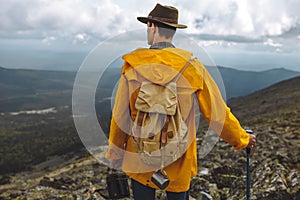 Young man in yellow raincoat spending time in mountain