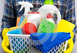 A young man in yellow rubber gloves holds cleaners and detergents. Spring cleaning in the house. Close-up. Selective focus