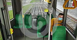 A young man in a yellow sweater and protective mask sits in an empty tram. Coronavirus epidemic in the world