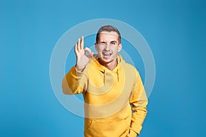 young man in yellow sweatshirt showing Ok gesture