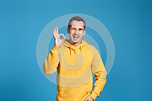 young man in yellow sweatshirt showing Ok gesture