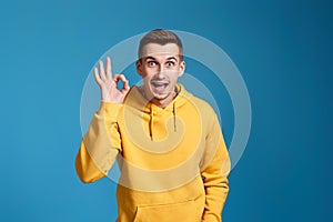 young man in yellow sweatshirt showing Ok gesture