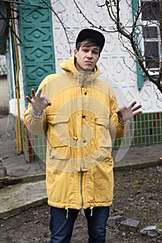 A young man in a yellow windbreaker, shows that he is doing fine.hip hop guyn