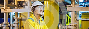 Young man in a yellow work uniform, glasses and helmet in industrial environment,oil Platform or liquefied gas plant