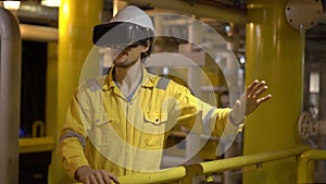 Young man in a yellow work uniform in industrial environment,oil Platform or liquefied gas plant uses VR glasses
