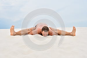 Young man in yoga pose kurmasana