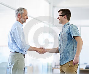 Young man...youve got yourself a deal. two businessmen shaking hands in the office.